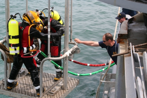 US Navy 060508-F-6344A-002 Senior Chief Navy Diver Clifford Morin aboard rescue and salvage ship USS Safeguard (ARS 50) tends the dive stage as fellow divers are lowered into the Yellow Sea during a major recovery effort